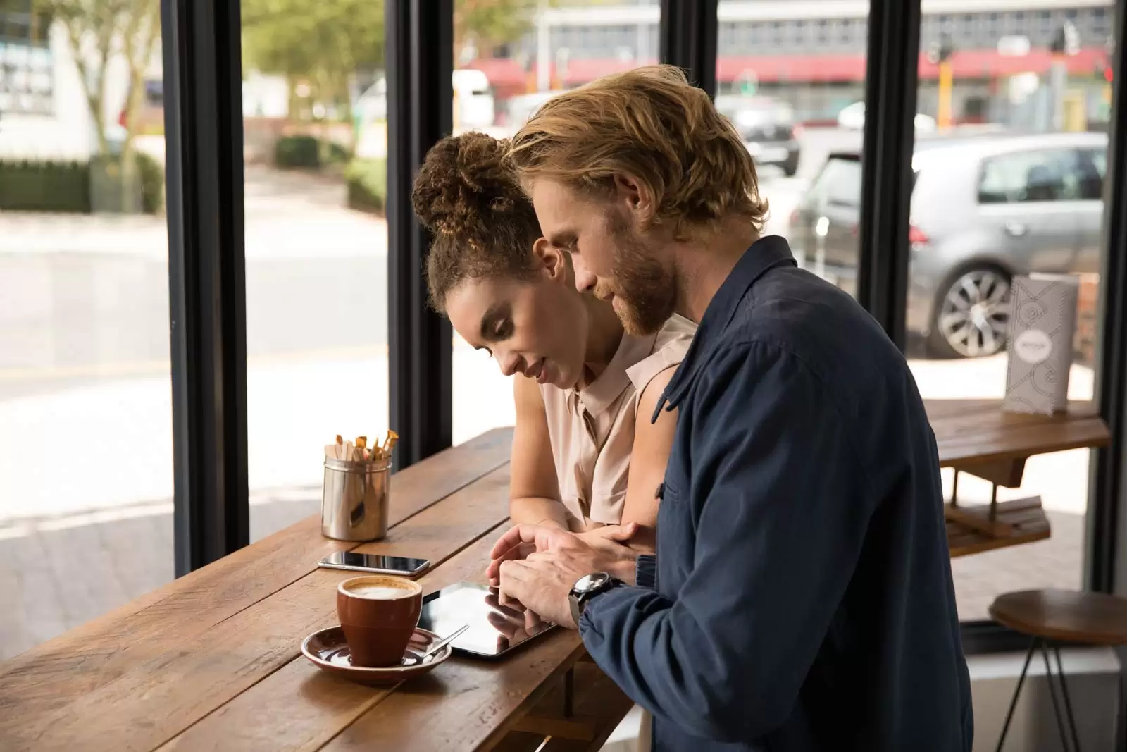 Paar sitzt im Café und nutzt Banking-App auf Tablet